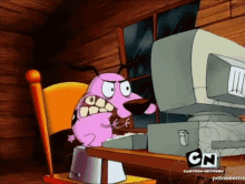 courage the cowardly dog is sitting at a desk looking at a computer monitor