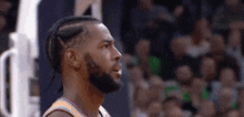 a basketball player with braids on his hair and a beard is looking up at the crowd during a game .