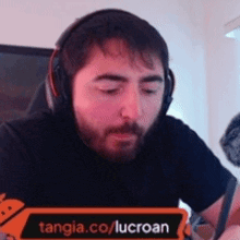 a man wearing headphones is sitting in front of a sign that says tangia.com/lucroan