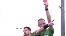 a referee is giving a red card to a player in a soccer game .