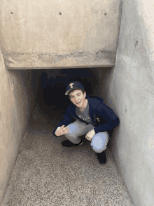 a young man wearing a hat with the letter t on it is kneeling down in a tunnel