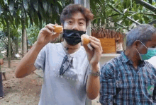 a man wearing a face mask is eating a donut while wearing a shirt that says a future is certain