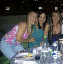 a bottle of crista water sits on a table with three women