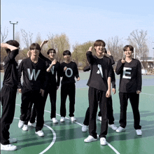 a group of young men are standing on a basketball court wearing black shirts with the letter w and o on them