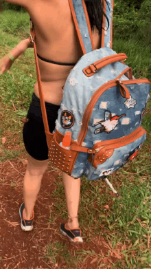 a woman carrying a denim backpack with a patch on it that says ' snoopy '