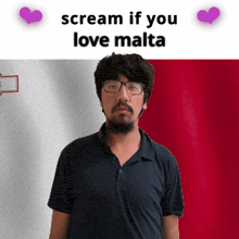 a man with glasses and a beard stands in front of a malta flag