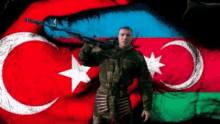 a soldier is holding a gun in front of a flag of azerbaijan .