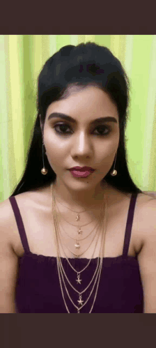 a close up of a woman wearing a purple top and a gold necklace