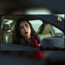 a woman is sitting in a car with a hum tv logo on the bottom