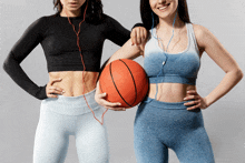 two women standing next to each other holding basketballs