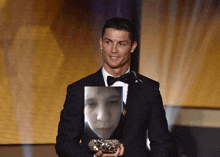 a man in a suit and bow tie is holding a picture of a man 's face