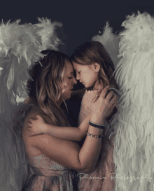 a woman and a little girl wearing angel wings are hugging