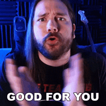 a man with long hair and a beard says good for you with his hands in the air