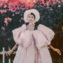 a woman wearing a pink dress and a white hat