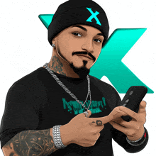 a man wearing a beanie with the letter x on it is holding a cell phone