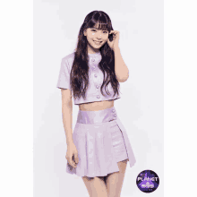 a girl in a purple crop top and skirt is standing in front of a white background