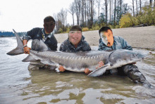 two men holding a large fish in the water with their faces obscured