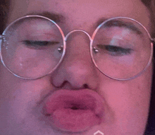 a close up of a person wearing round glasses making a face