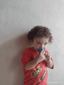 a young boy wearing a red shirt with cars on it