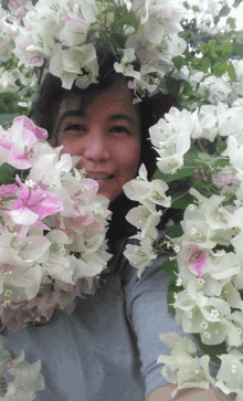 a woman surrounded by pink and white flowers is smiling