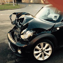 a black mini cooper with a damaged front bumper