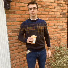 a man in a plaid sweater holds a starbucks cup