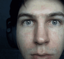 a close up of a man 's face with blue eyes and headphones