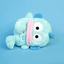 a blue stuffed animal with big eyes and a pink tongue on a blue background