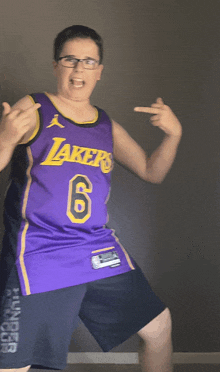 a boy wearing a purple lakers jersey is giving the middle finger