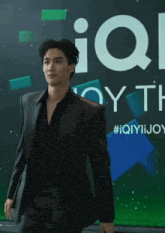 a man in a black suit is standing in front of a large sign that says iq