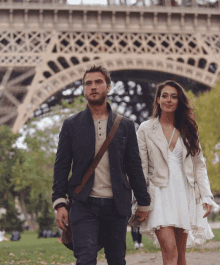 a man and a woman walking in front of the eiffel tower