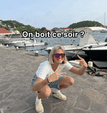 a woman is squatting down in front of boats with the words on boit ce soir on the bottom