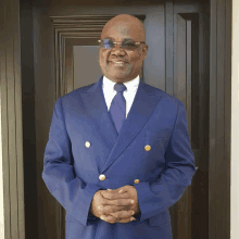 a man in a blue suit and tie is standing in front of a door