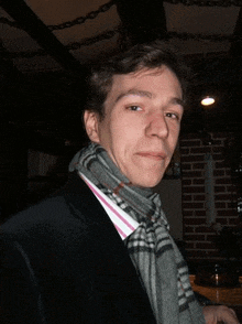 a man wearing a scarf and a suit looks at the camera