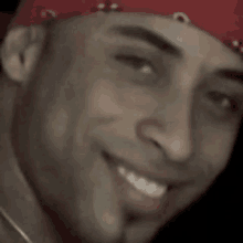 a man wearing a red bandana and a necklace is smiling .