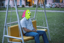 a man sits on a swing with a cartoon face on his face