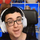 a man wearing headphones and glasses is smiling in front of a shelf of stuffed animals .