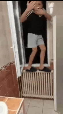 a man is standing on a radiator next to a window in a bathroom .