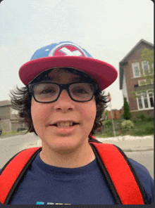 a young boy wearing a hat and glasses is smiling .