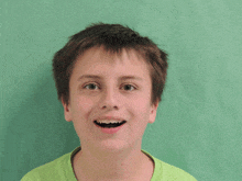 a young boy wearing a green shirt with his mouth wide open