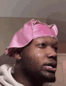 a man wearing a pink hat with a tear running down his face