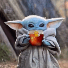 a baby yoda from the mandalorian is drinking a cup of lipton tea .