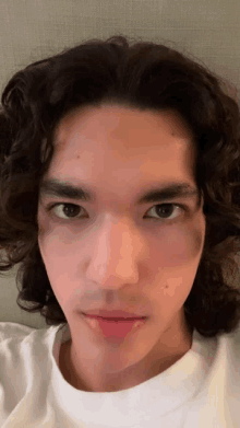 a young man with long curly hair is taking a selfie