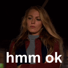 a woman in a red jacket is standing in front of a sign that says hmm ok