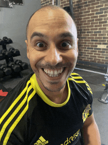 a man in a black and yellow adidas shirt smiles