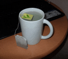 a white mug with a tea bag in it sits on a wooden table