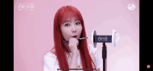 a girl with red hair holds a brush in her mouth in front of a microphone