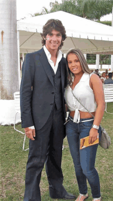 a man in a suit and a woman in a white crop top pose for a picture