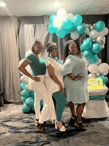 three women are posing for a picture in front of balloons and a sign with the number 5 on it