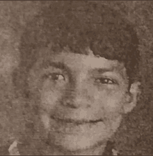 a black and white photo of a young boy smiling .